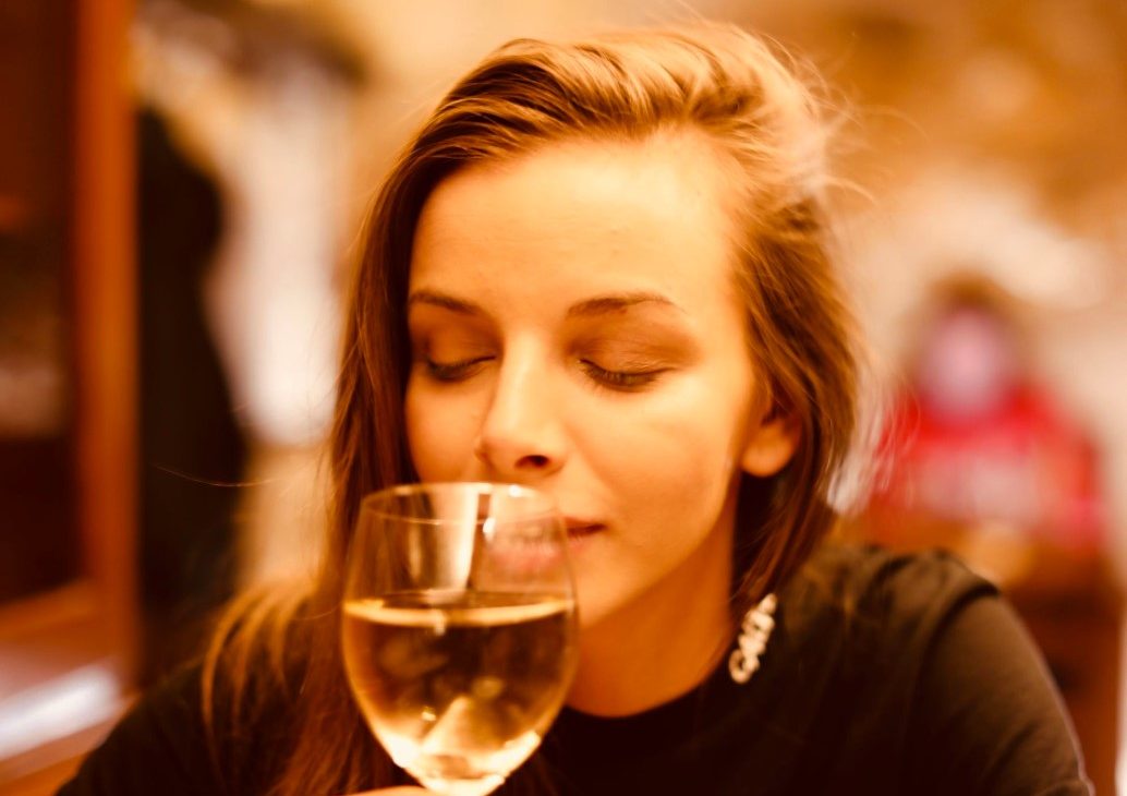 Woman smelling from wine cup.