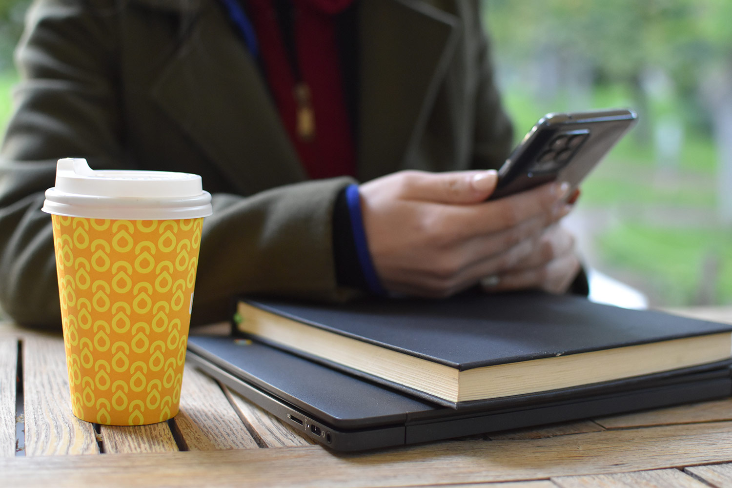 Coffee cup and female hands with smartphone