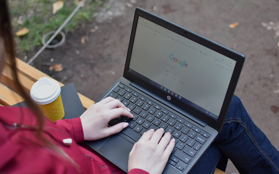 Female with laptop and coffee in the park