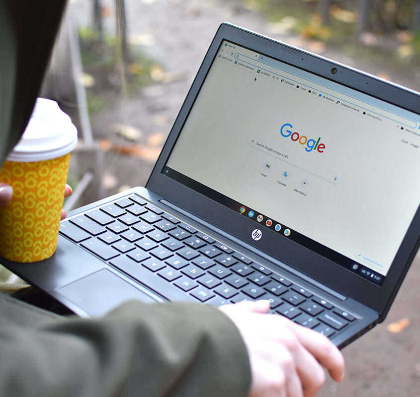 Woman working on laptop and drinking a coffee in the park